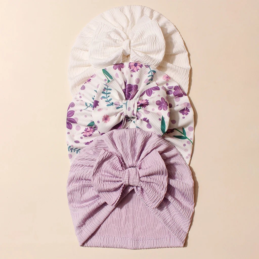 Three baby headbands, one with a floral pattern, the other solid color, and a solid White on a beige background.