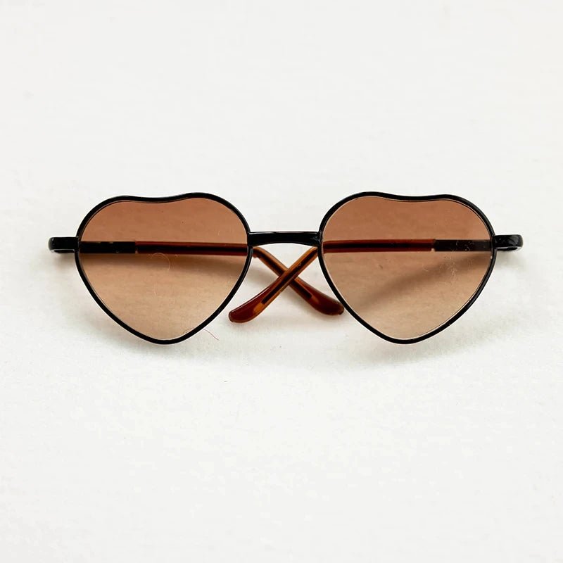 Heart-shaped sunglasses with brown lenses on a white background