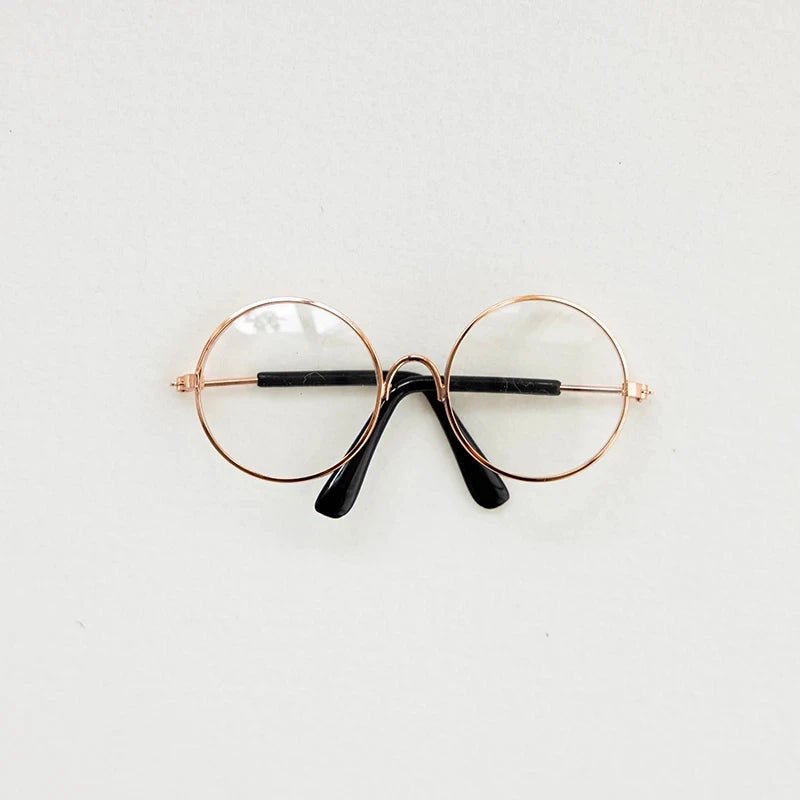 Round eyeglasses with rose gold frame and black arms on a light gray background