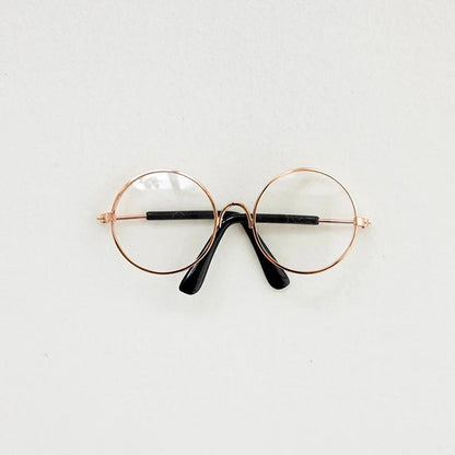 Round eyeglasses with rose gold frame and black arms on a light gray background