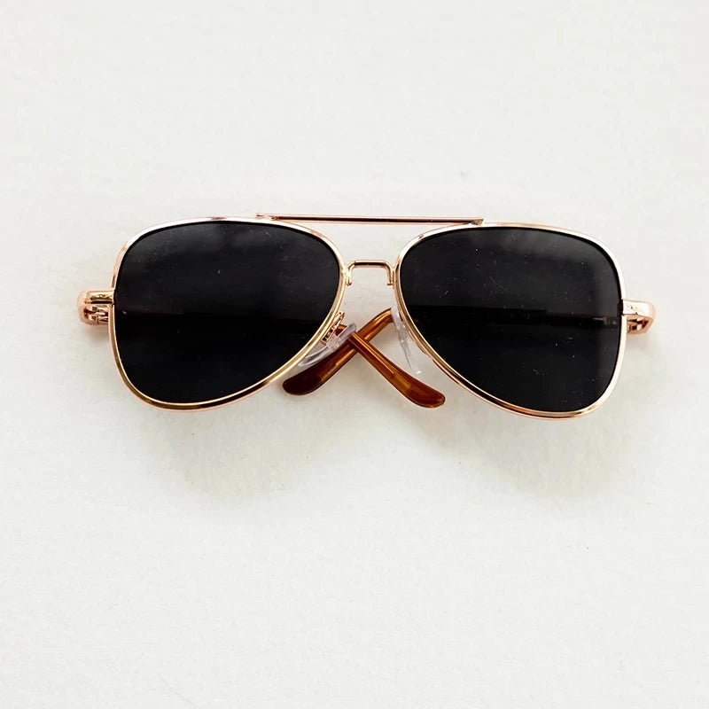 Aviator sunglasses with gold frame and black lenses on a white background