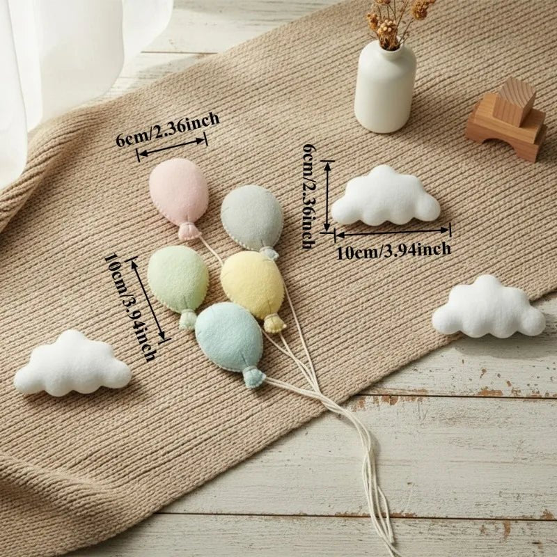 Decorative cloud and balloon ornaments with measurements on a textured surface.