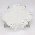 A round white fringed textile piece, likely a decorative mat or cushion cover, displayed on a distressed metal stand against a plain white background.