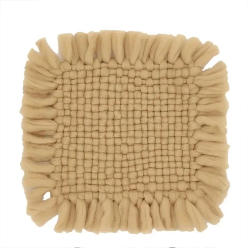 A square beige bath mat with a textured woven center and fringed edges, shown against a plain white background.