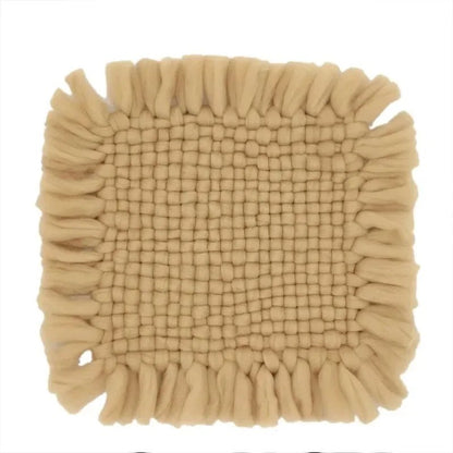 A square beige bath mat with a textured woven center and fringed edges, shown against a plain white background.