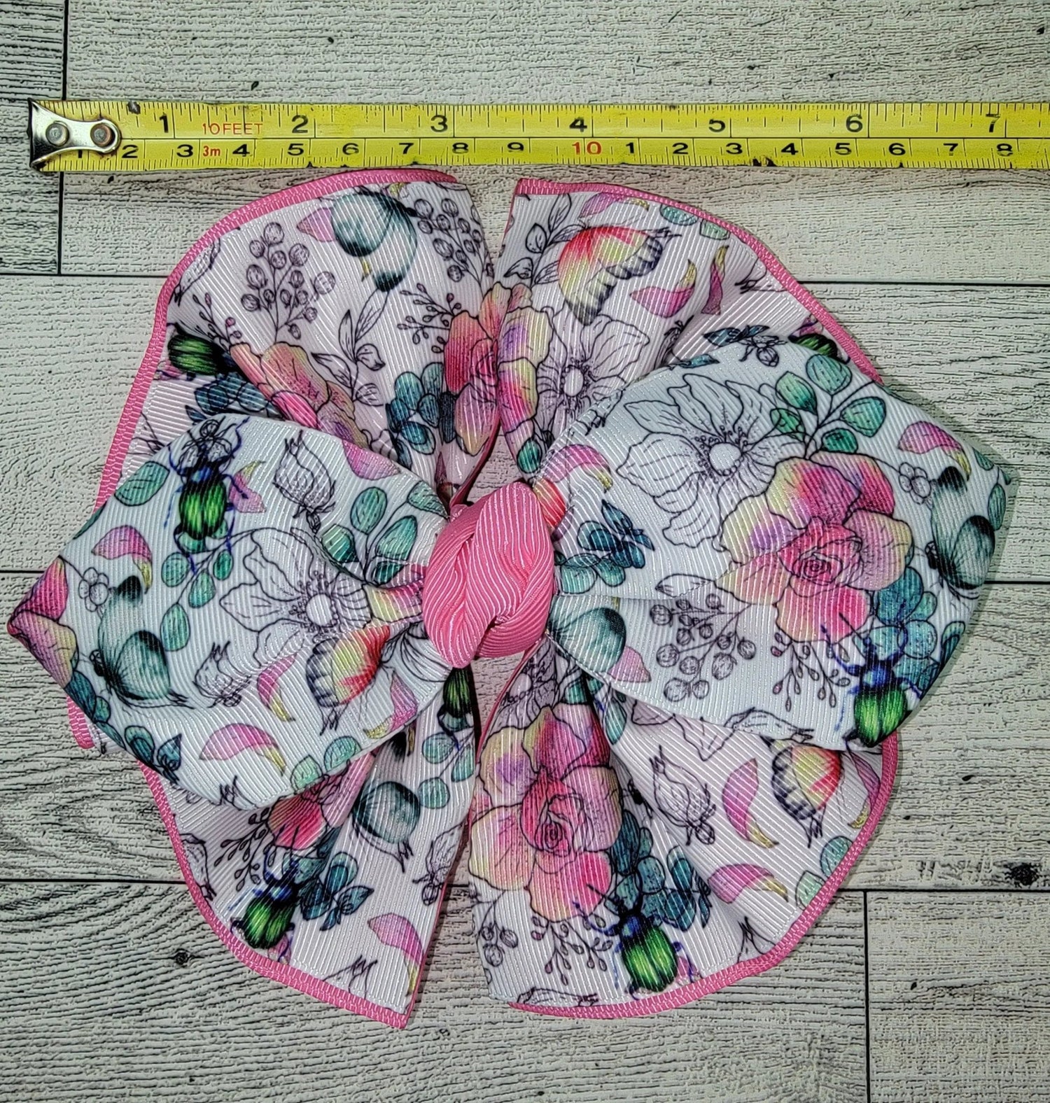 Floral fabric bow with a measuring tape on a wooden surface
