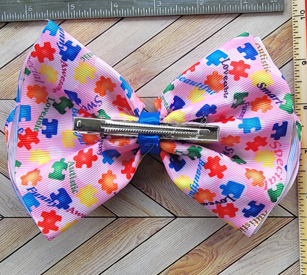 Colorful bow with puzzle piece pattern on a wooden surface with a ruler for scale.