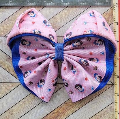 Large pink and blue bow with character pattern on a wooden surface with a ruler for scale.