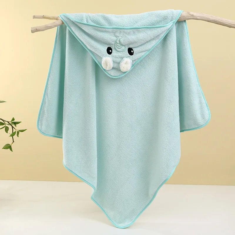 Light blue hooded towel with cartoon face on a branch against a beige background