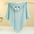 Light blue hooded towel with cartoon face on a branch against a beige background