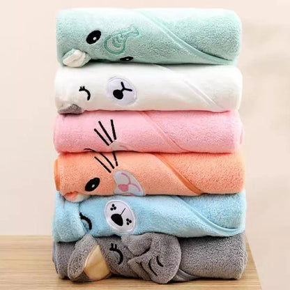 Stack of colorful towels with cartoon animal faces on a wooden surface.