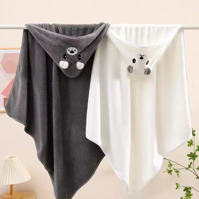 Two baby blankets with cartoon faces, one gray and one white, hanging on a rack.