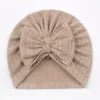 Beige knitted headband with a bow on a plain background
