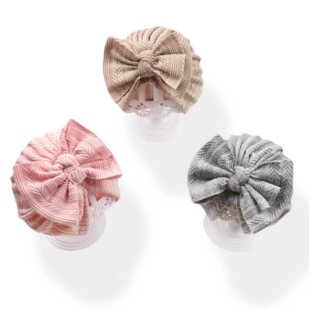 Three baby headbands in beige, pink, and gray on a white background