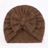 Brown knitted turban with a bow on a plain background