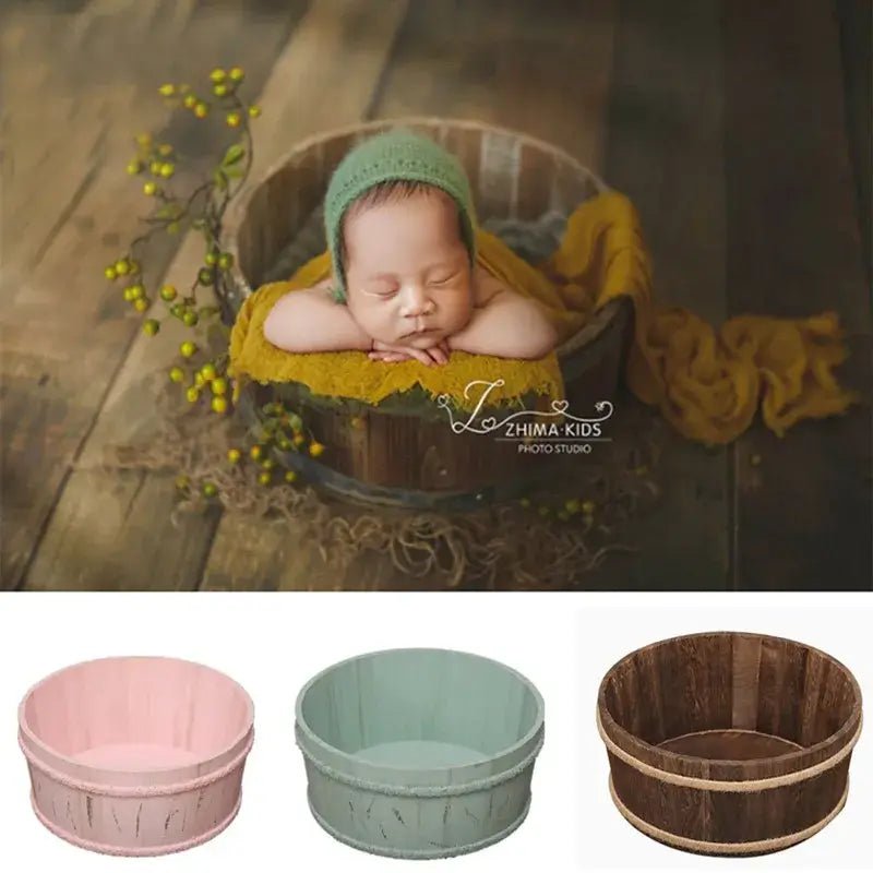 Newborn baby in a wooden bucket with green bonnet and yellow blanket, ZHIMA KIDS studio logo.