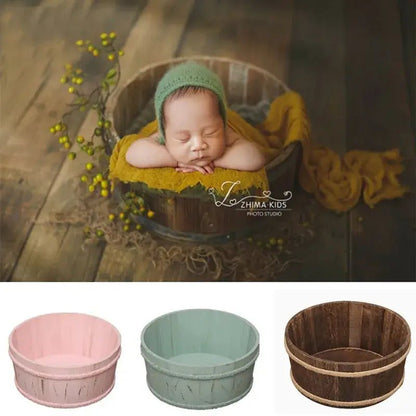 Newborn baby in a wooden bucket with green bonnet and yellow blanket, ZHIMA KIDS studio logo.
