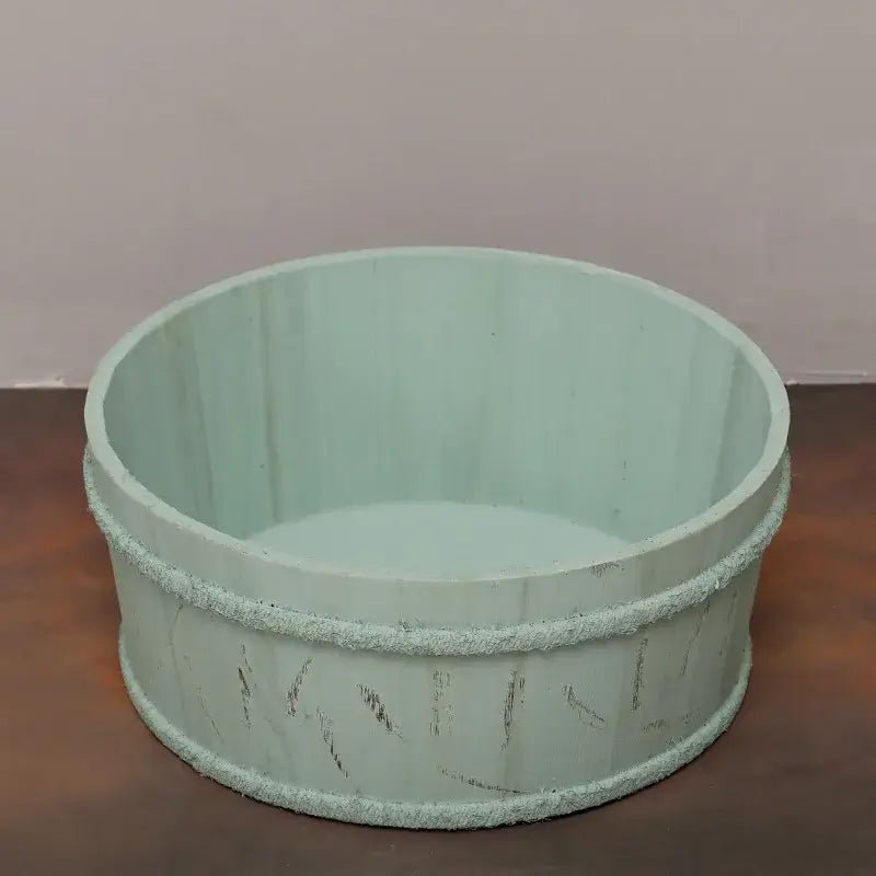 Light green pet bed on a wooden surface with a neutral background
